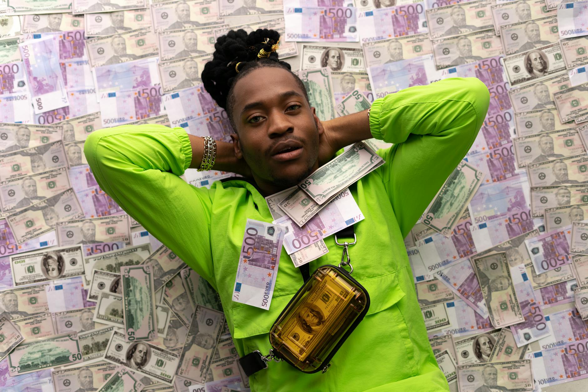 man in green jacket lying down on money